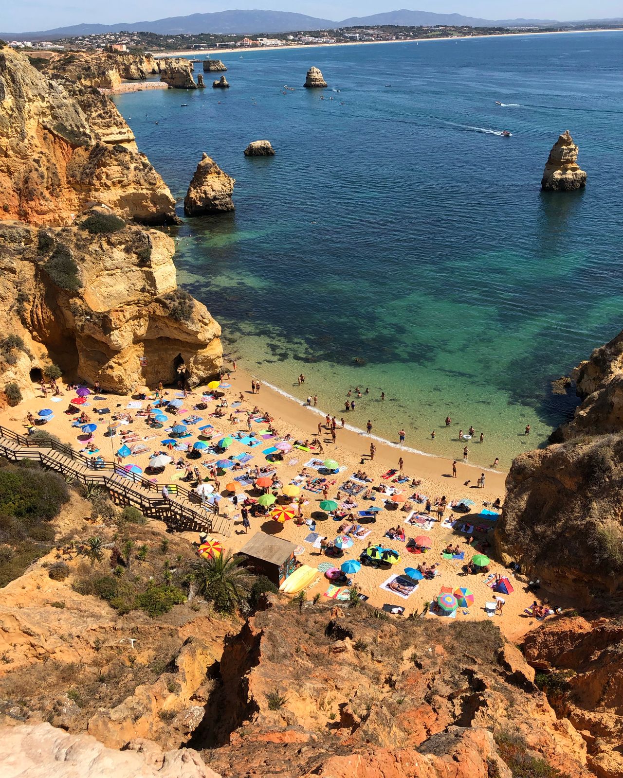 A beach below the cliffs at Faro, parasols and swimmers in the shallows